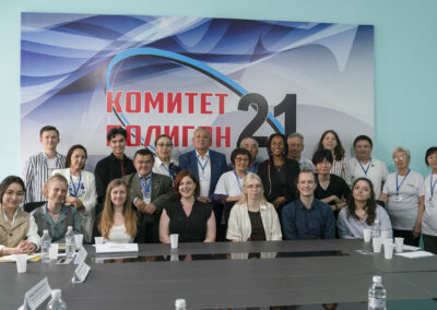 Eine Gruppe Menschen vor einem Plakat mit der Aufschrift "Komitet [unleserlich] 21" posierend.