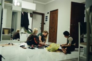 Kindersitzen in einem Kunstmuseum auf dem Boden und hören den Kuratoren zu.