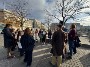 Kindersitzen in einem Kunstmuseum auf dem Boden und hören den Kuratoren zu.